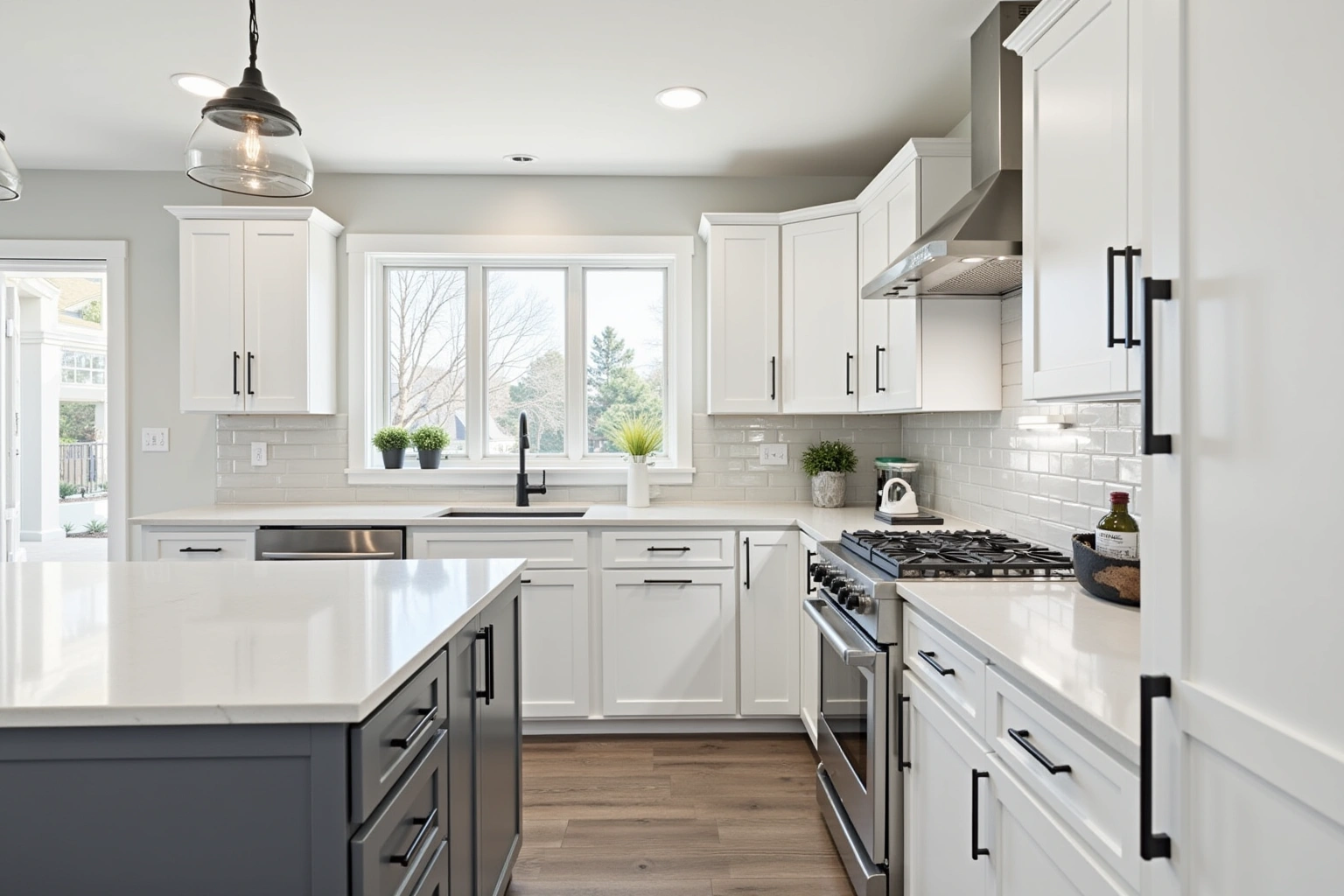 White shaker kitchen with matte black pulls, a grey island, glossy subway tile and white quartz counters.